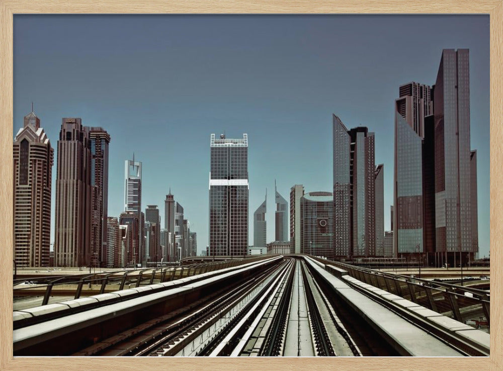 A view from an elevated train track looking down the rails towards the towering skyscrapers of a modern city skyline, under a clear, muted blue sky. Wall Art