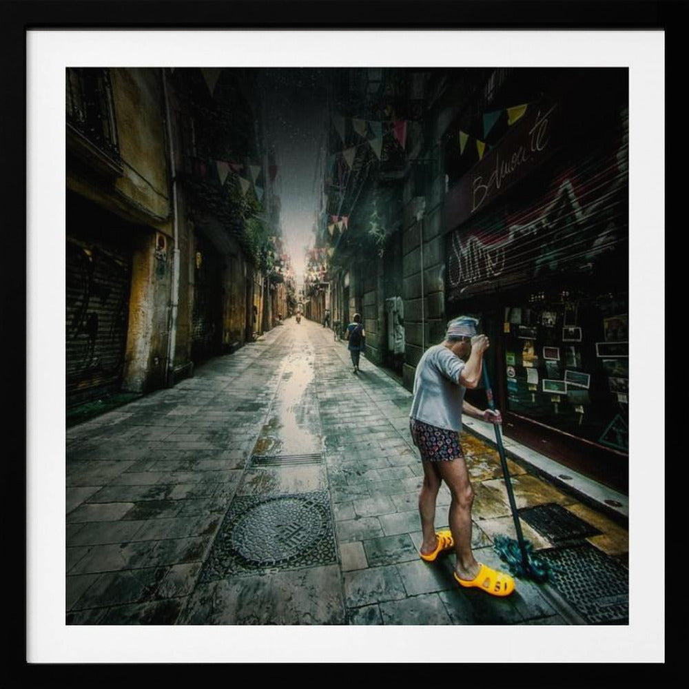 A wide-angle, atmospheric photograph of a man in bright yellow clogs mopping a wet, narrow cobblestone alley. The dark, gritty city street is lined with old buildings and closed storefronts, with another person walking in the distant light at the end of the alley. Wall Art