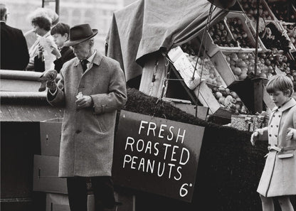A vintage black and white photograph of an elderly man in a fedora and overcoat feeding a pigeon from his hand at an outdoor market. A sign for 'FRESH ROASTED PEANUTS' is visible next to him, and a young boy in a coat watches nearby. Wall Art