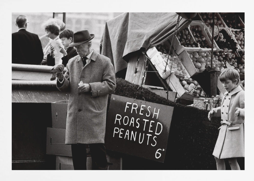 A vintage black and white photograph of an elderly man in a fedora and overcoat feeding a pigeon from his hand at an outdoor market. A sign for 'FRESH ROASTED PEANUTS' is visible next to him, and a young boy in a coat watches nearby. Wall Art