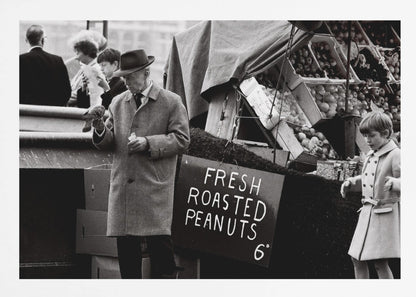 A vintage black and white photograph of an elderly man in a fedora and overcoat feeding a pigeon from his hand at an outdoor market. A sign for 'FRESH ROASTED PEANUTS' is visible next to him, and a young boy in a coat watches nearby. Wall Art