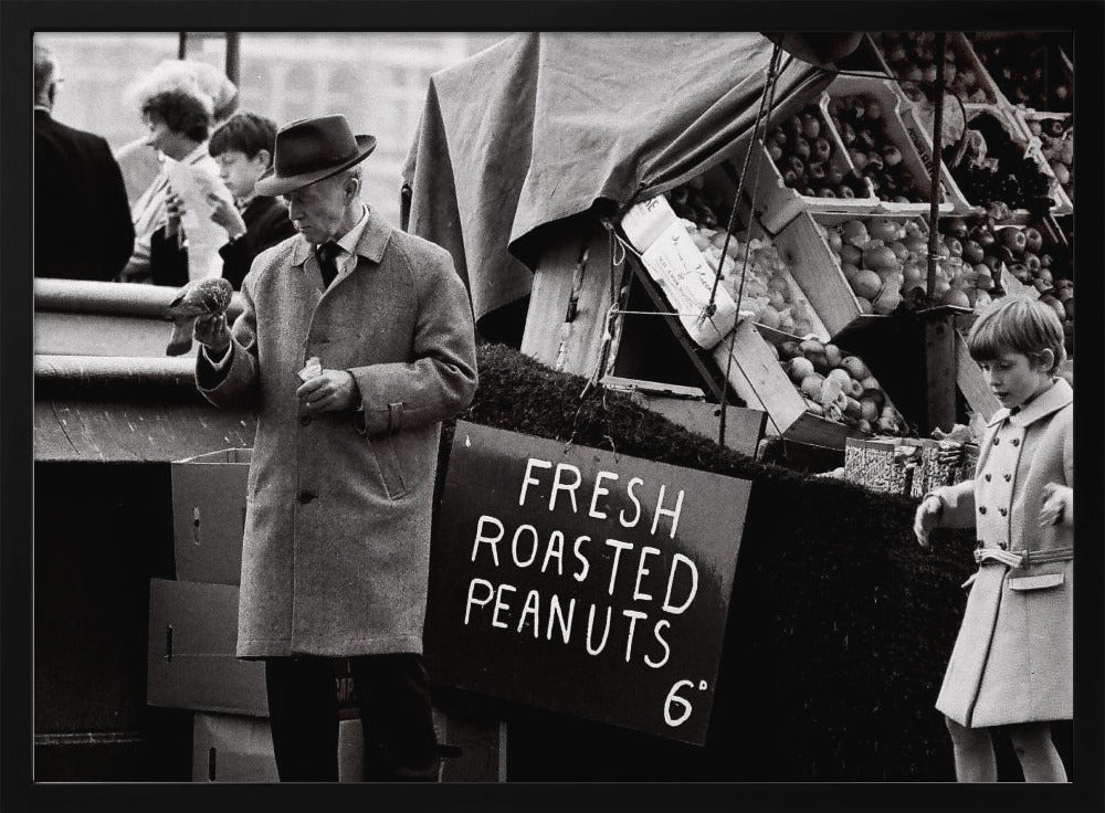 A vintage black and white photograph of an elderly man in a fedora and overcoat feeding a pigeon from his hand at an outdoor market. A sign for 'FRESH ROASTED PEANUTS' is visible next to him, and a young boy in a coat watches nearby. Wall Art