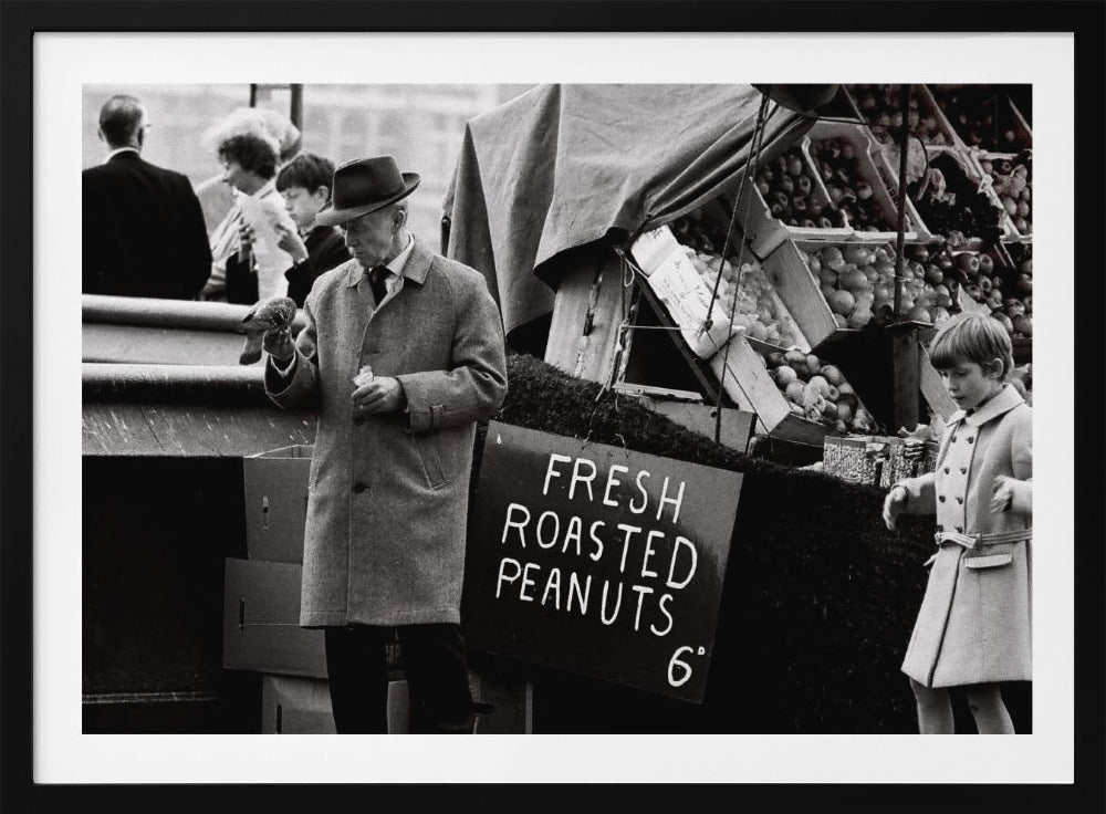 A vintage black and white photograph of an elderly man in a fedora and overcoat feeding a pigeon from his hand at an outdoor market. A sign for 'FRESH ROASTED PEANUTS' is visible next to him, and a young boy in a coat watches nearby. Wall Art