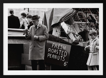 A vintage black and white photograph of an elderly man in a fedora and overcoat feeding a pigeon from his hand at an outdoor market. A sign for 'FRESH ROASTED PEANUTS' is visible next to him, and a young boy in a coat watches nearby. Wall Art