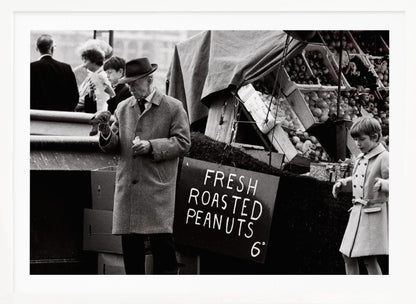 A vintage black and white photograph of an elderly man in a fedora and overcoat feeding a pigeon from his hand at an outdoor market. A sign for 'FRESH ROASTED PEANUTS' is visible next to him, and a young boy in a coat watches nearby. Wall Art