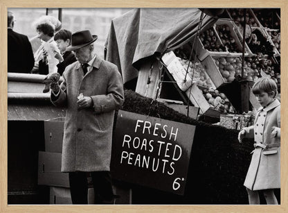 A vintage black and white photograph of an elderly man in a fedora and overcoat feeding a pigeon from his hand at an outdoor market. A sign for 'FRESH ROASTED PEANUTS' is visible next to him, and a young boy in a coat watches nearby. Wall Art