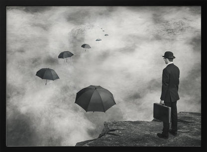 A surreal black and white photograph of a man in a suit and bowler hat holding a briefcase, standing on a cliff edge. He gazes into a foggy expanse where a path of floating black umbrellas leads into the misty distance. Decor