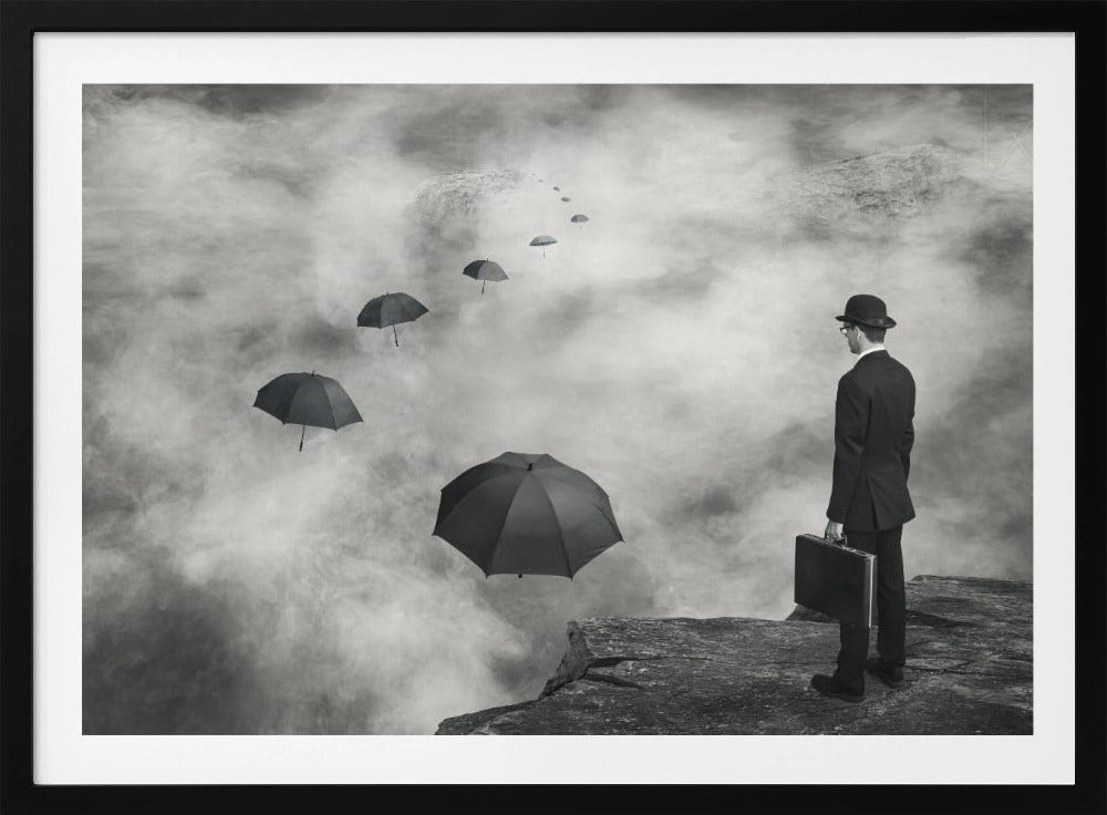 A surreal black and white photograph of a man in a suit and bowler hat holding a briefcase, standing on a cliff edge. He gazes into a foggy expanse where a path of floating black umbrellas leads into the misty distance. Decor