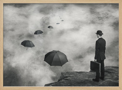 A surreal black and white photograph of a man in a suit and bowler hat holding a briefcase, standing on a cliff edge. He gazes into a foggy expanse where a path of floating black umbrellas leads into the misty distance. Decor