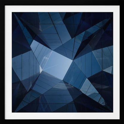 A framed, low-angle photograph looking up towards the sky, surrounded by the reflective blue glass facades of modern buildings which create a kaleidoscopic, geometric pattern. Print