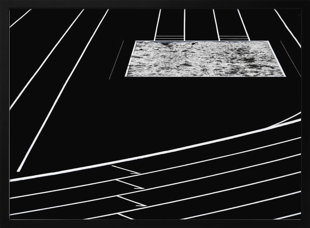 A high-contrast, black and white abstract artwork depicting a running track from an elevated perspective. Stark white lines representing lanes curve across a solid black background. In the upper portion, a rectangular shape filled with a textured, water-like pattern replaces a typical sand pit. The entire piece is presented within a silver frame. Print