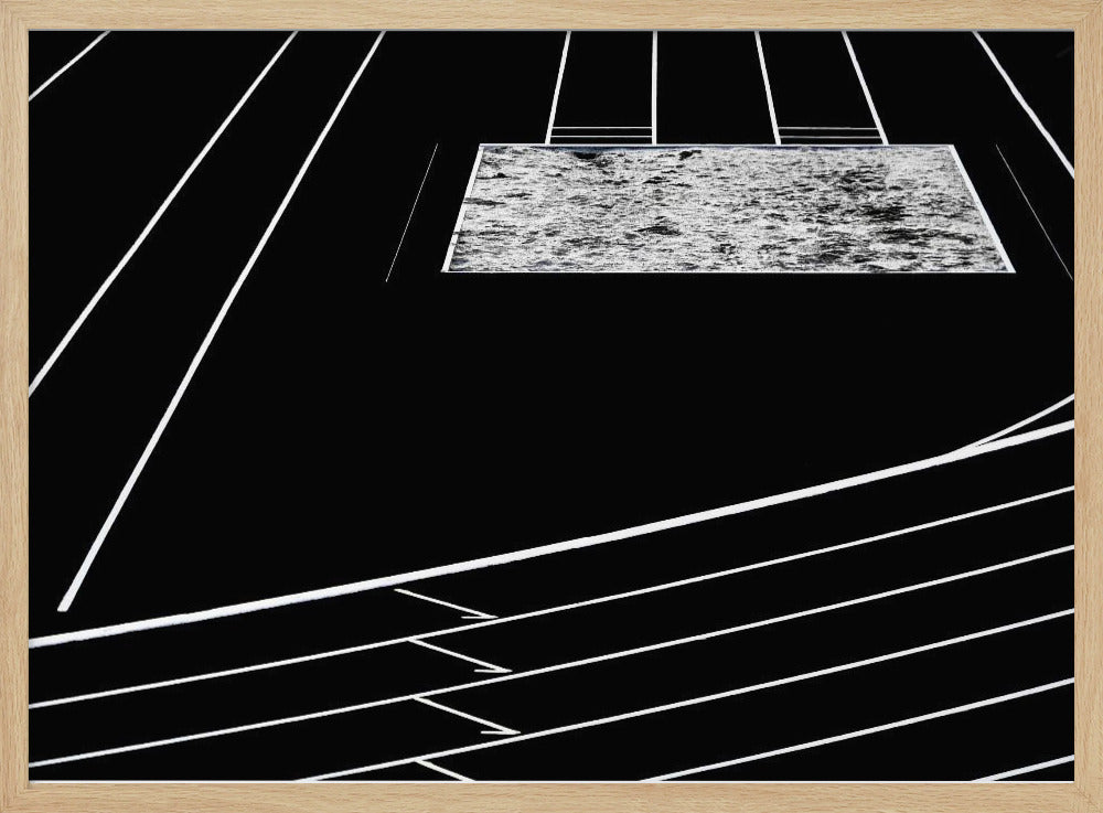 A high-contrast, black and white abstract artwork depicting a running track from an elevated perspective. Stark white lines representing lanes curve across a solid black background. In the upper portion, a rectangular shape filled with a textured, water-like pattern replaces a typical sand pit. The entire piece is presented within a silver frame. Print