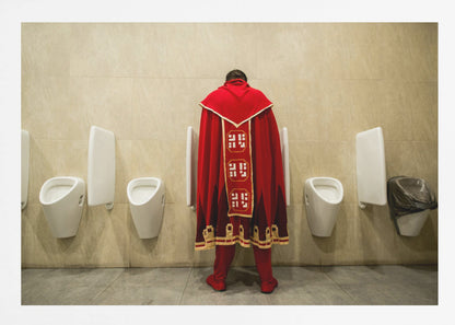 A back view of a person wearing an elaborate, long red and gold cape, standing at a urinal in a modern public restroom with beige tiled walls and multiple white urinals. Artwork