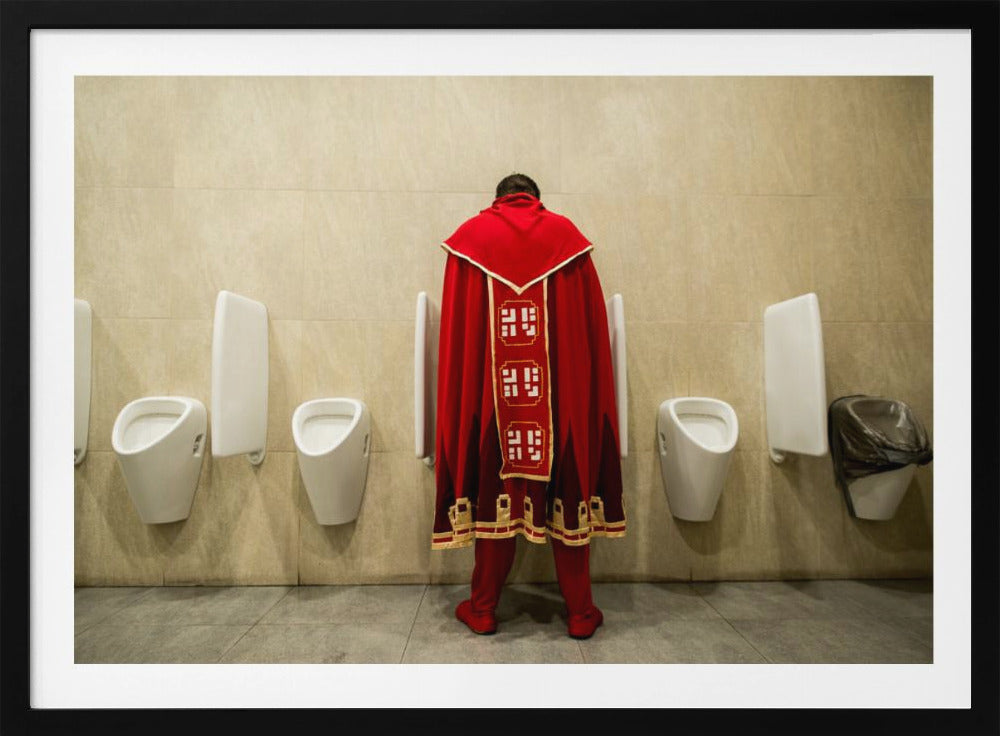 A back view of a person wearing an elaborate, long red and gold cape, standing at a urinal in a modern public restroom with beige tiled walls and multiple white urinals. Artwork