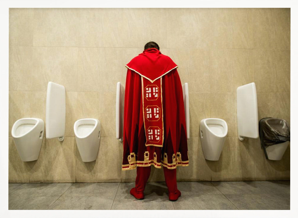 A back view of a person wearing an elaborate, long red and gold cape, standing at a urinal in a modern public restroom with beige tiled walls and multiple white urinals. Artwork