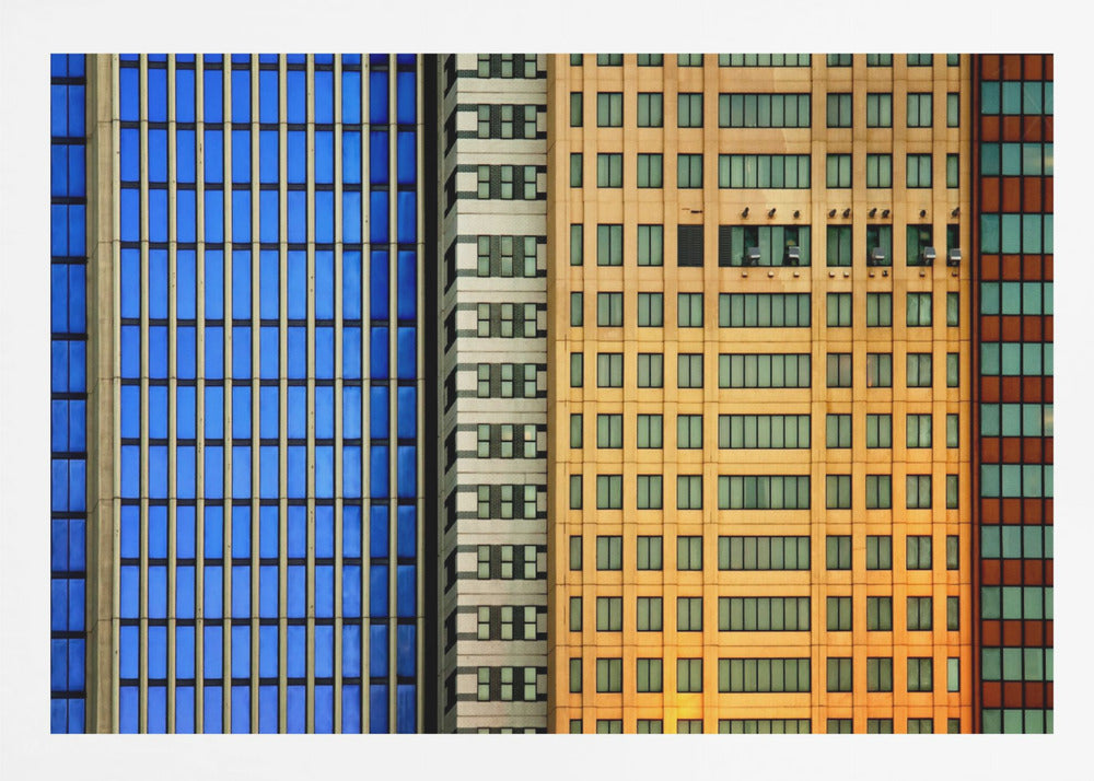 An abstract architectural photograph showing the colorful gridded facades of three adjacent skyscrapers, featuring a blue-windowed building, a white building, and a yellow building, all contained within a silver frame. Wall Art
