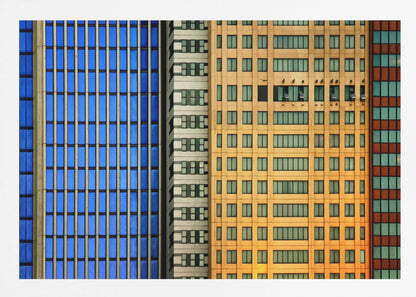 An abstract architectural photograph showing the colorful gridded facades of three adjacent skyscrapers, featuring a blue-windowed building, a white building, and a yellow building, all contained within a silver frame. Wall Art