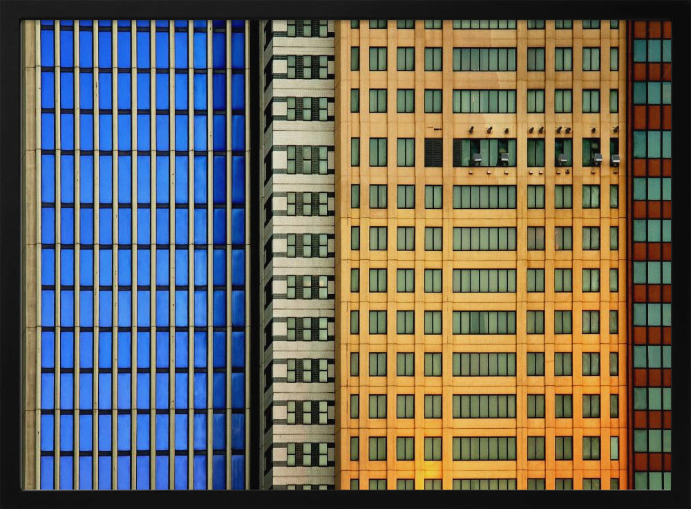 An abstract architectural photograph showing the colorful gridded facades of three adjacent skyscrapers, featuring a blue-windowed building, a white building, and a yellow building, all contained within a silver frame. Wall Art