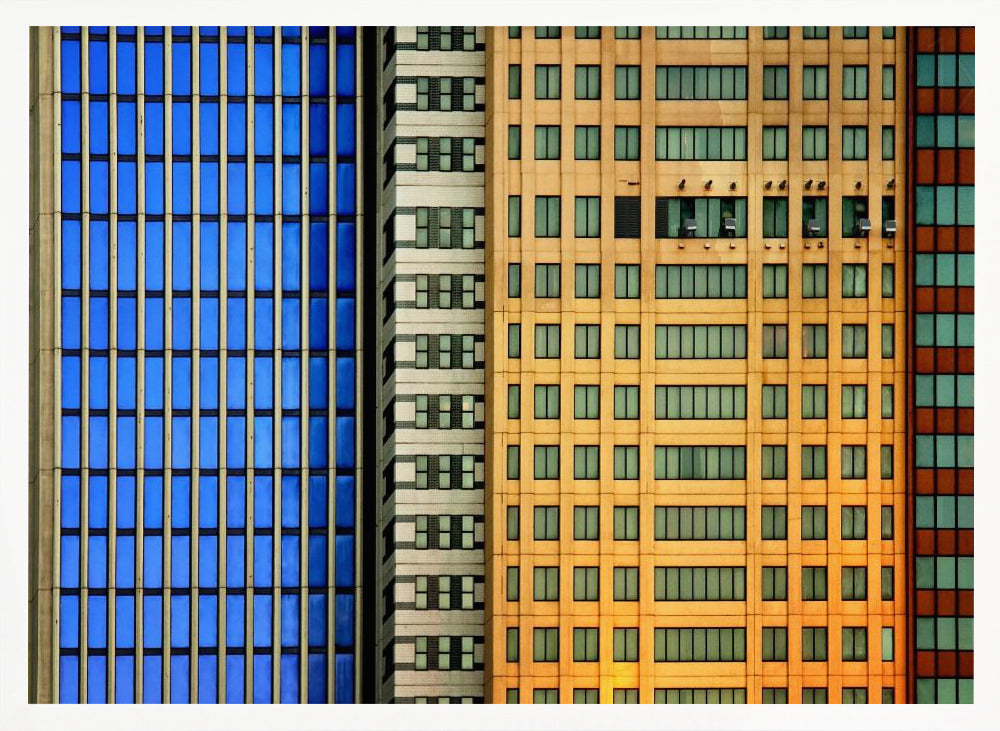 An abstract architectural photograph showing the colorful gridded facades of three adjacent skyscrapers, featuring a blue-windowed building, a white building, and a yellow building, all contained within a silver frame. Wall Art