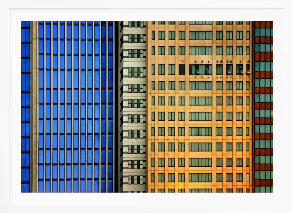 An abstract architectural photograph showing the colorful gridded facades of three adjacent skyscrapers, featuring a blue-windowed building, a white building, and a yellow building, all contained within a silver frame. Wall Art