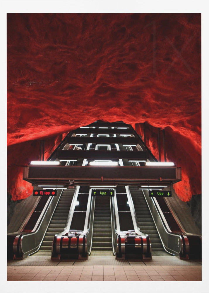 A dramatic low-angle shot looking up a series of escalators in a subway station with a cavernous, rough-textured ceiling glowing an intense, fiery red. Decor