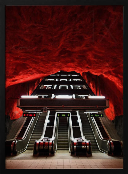 A dramatic low-angle shot looking up a series of escalators in a subway station with a cavernous, rough-textured ceiling glowing an intense, fiery red. Decor