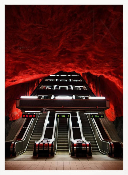 A dramatic low-angle shot looking up a series of escalators in a subway station with a cavernous, rough-textured ceiling glowing an intense, fiery red. Decor
