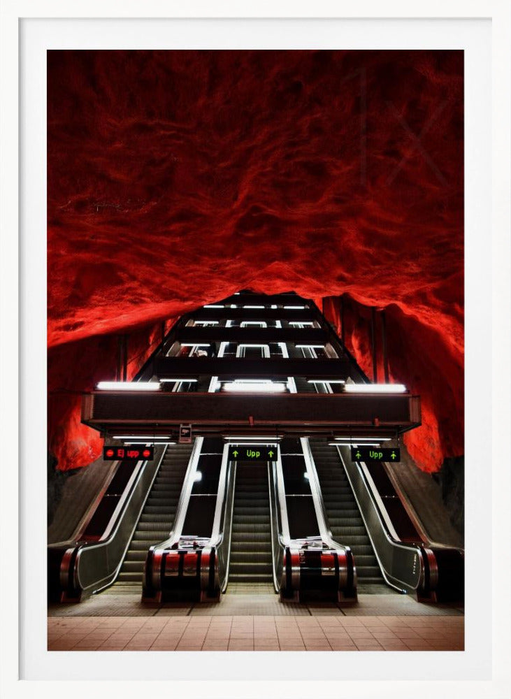 A dramatic low-angle shot looking up a series of escalators in a subway station with a cavernous, rough-textured ceiling glowing an intense, fiery red. Decor