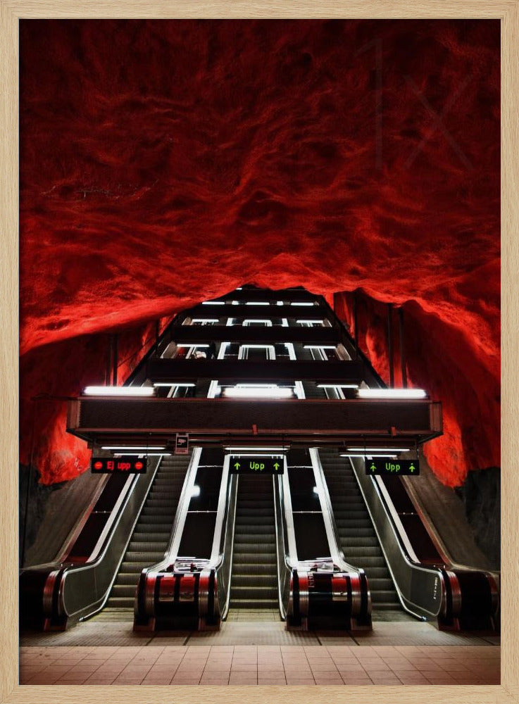 A dramatic low-angle shot looking up a series of escalators in a subway station with a cavernous, rough-textured ceiling glowing an intense, fiery red. Decor