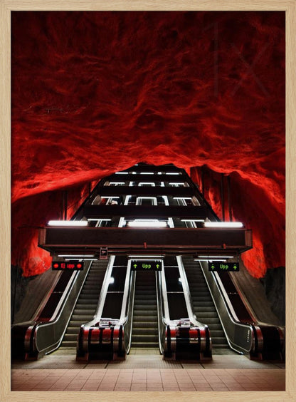 A dramatic low-angle shot looking up a series of escalators in a subway station with a cavernous, rough-textured ceiling glowing an intense, fiery red. Decor