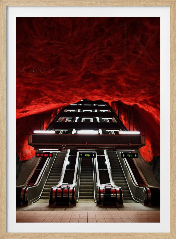 A dramatic low-angle shot looking up a series of escalators in a subway station with a cavernous, rough-textured ceiling glowing an intense, fiery red. Decor