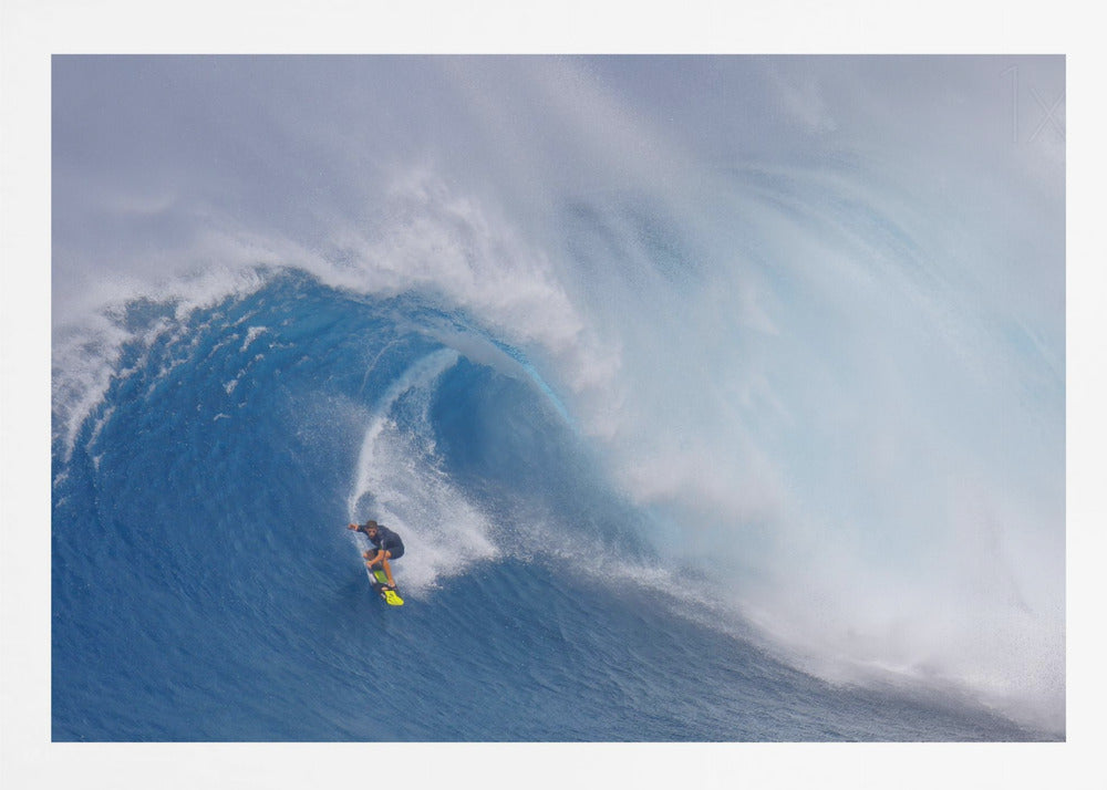 A framed photograph of a professional surfer skillfully riding down the steep face of a massive, cresting blue ocean wave, surrounded by white sea spray. Decor