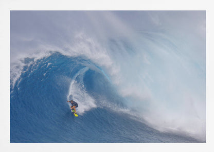 A framed photograph of a professional surfer skillfully riding down the steep face of a massive, cresting blue ocean wave, surrounded by white sea spray. Decor