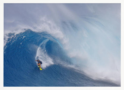 A framed photograph of a professional surfer skillfully riding down the steep face of a massive, cresting blue ocean wave, surrounded by white sea spray. Decor