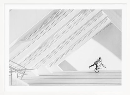 A minimalist black and white photograph in a silver frame, featuring a lone BMX rider performing a trick on the back wheel inside a stark, modern building with strong diagonal architectural lines. Poster