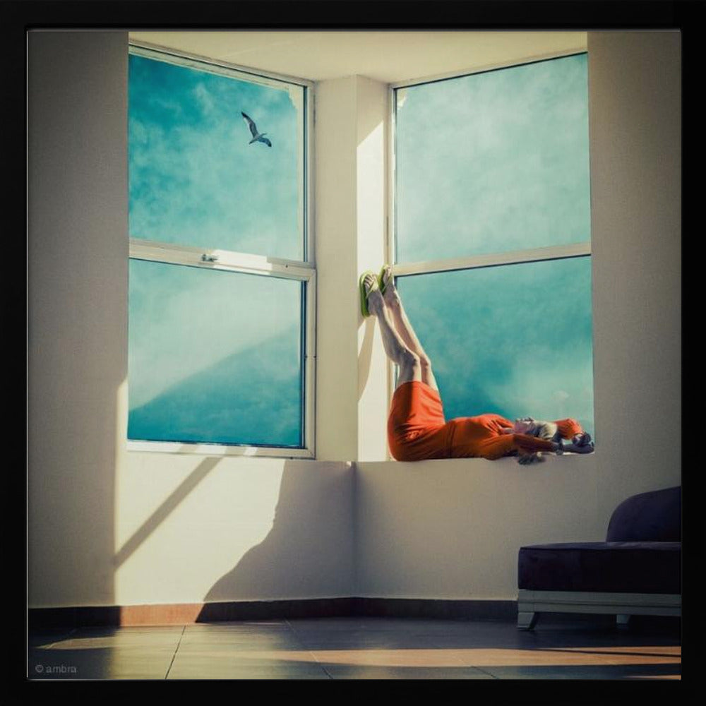 A surreal photograph of a woman in a bright orange dress lying on a wide, sunlit windowsill with her legs up against the wall. Through the large windows, a single bird is seen flying in a vibrant teal sky. The image, presented in a light wood frame, captures a moment of quiet contemplation and escape. Wall Art