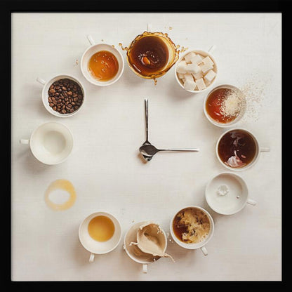 A creative flat lay photograph of a clock made from coffee cups and ingredients. Twelve white cups are arranged in a circle on a white background, each representing an hour and filled with different coffee-related items like beans, honey, sugar cubes, and various stages of coffee with milk splashing. In the center, two silver spoons form the hands of the clock. The entire image is presented within a light wood frame. Decor