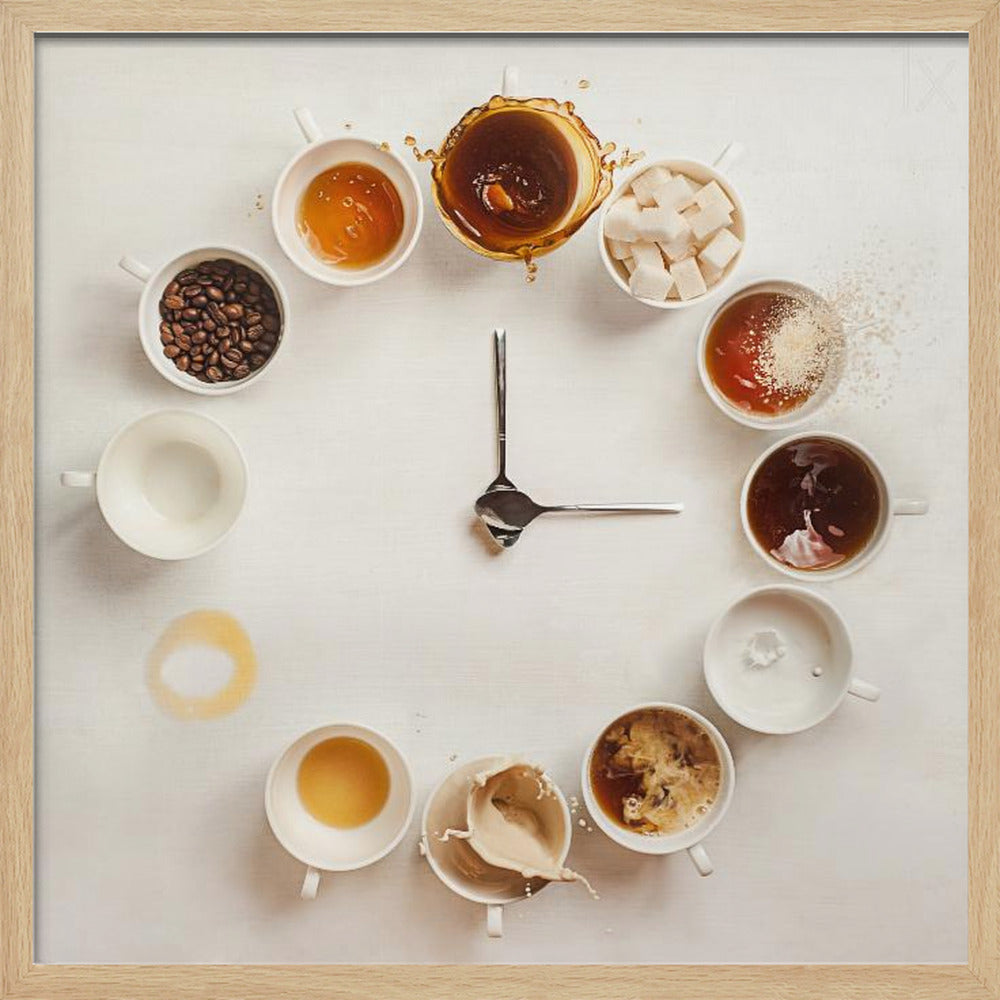 A creative flat lay photograph of a clock made from coffee cups and ingredients. Twelve white cups are arranged in a circle on a white background, each representing an hour and filled with different coffee-related items like beans, honey, sugar cubes, and various stages of coffee with milk splashing. In the center, two silver spoons form the hands of the clock. The entire image is presented within a light wood frame. Decor