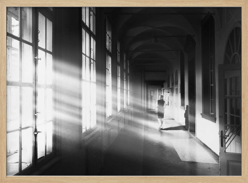 A black and white photograph of a woman walking away down a long, dark hallway. Bright shafts of sunlight pour through large windows on the left, creating a dramatic interplay of light and shadow on the floor and walls. Poster