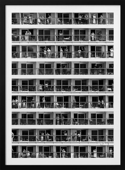 A black and white, high-contrast photograph of the side of a cruise ship, showing a grid of balconies across multiple decks. Various passengers are visible on their balconies, some waving, some relaxing, and some observing, creating a pattern of individual human stories within the repetitive architectural structure. Poster
