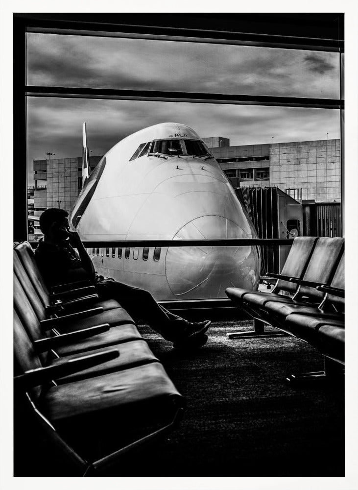 A dramatic black and white photograph of a silhouetted person sitting in an airport departure lounge, waiting for their flight. Through the large window, the enormous nose of a Boeing 747 jumbo jet is visible up close, dominating the view under a cloudy sky. Artwork