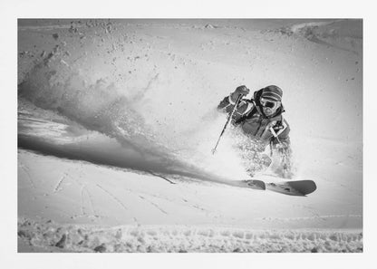 A framed, black and white action shot of a skier making a sharp turn on a snowy slope, sending a large spray of powder into the air. The skier is leaning into the turn, fully kitted out in winter gear including goggles and a beanie. Artwork