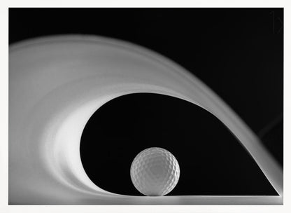 A dramatic black and white still life photo featuring a golf ball set against a stark black background. A large, abstract white shape swirls gracefully over the ball, creating a dynamic, wave-like composition. The image is presented within a silver frame. Decor