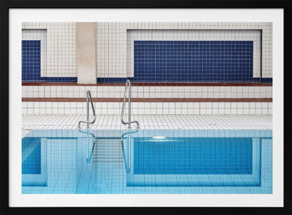 A framed, symmetrical photograph of a minimalist indoor swimming pool with blue and white tiles, stainless steel ladders, and a calm, reflective water surface. Poster