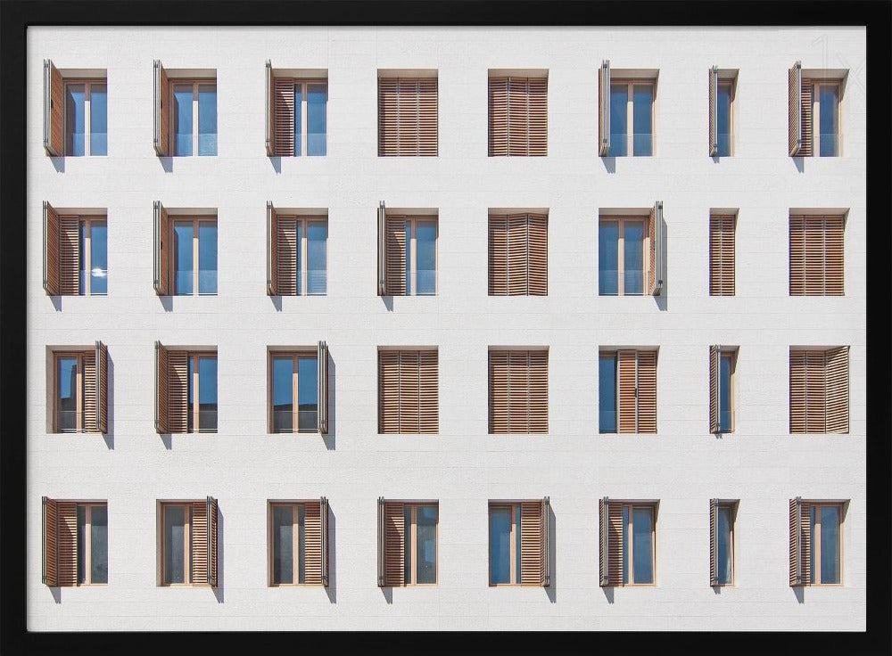 A symmetrical architectural photo of a modern white building facade featuring a grid of twenty-eight windows with wooden louvered shutters, some open and some closed, creating a varied pattern, all within a brushed silver frame. Decor
