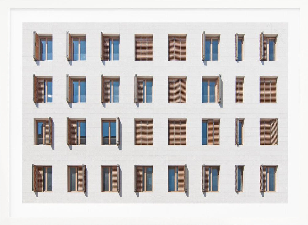 A symmetrical architectural photo of a modern white building facade featuring a grid of twenty-eight windows with wooden louvered shutters, some open and some closed, creating a varied pattern, all within a brushed silver frame. Decor