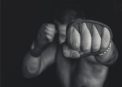 A dramatic black and white close-up photograph of a boxer's wrapped fist punching towards the camera. The fighter's body and other fist are blurred in the background, creating a powerful and intense mood. Print