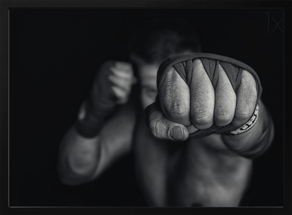 A dramatic black and white close-up photograph of a boxer's wrapped fist punching towards the camera. The fighter's body and other fist are blurred in the background, creating a powerful and intense mood. Print