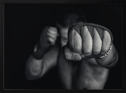 A dramatic black and white close-up photograph of a boxer's wrapped fist punching towards the camera. The fighter's body and other fist are blurred in the background, creating a powerful and intense mood. Print