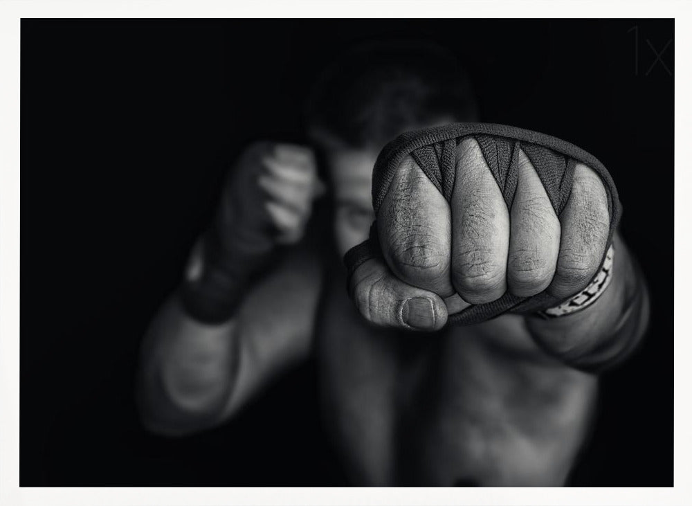 A dramatic black and white close-up photograph of a boxer's wrapped fist punching towards the camera. The fighter's body and other fist are blurred in the background, creating a powerful and intense mood. Print